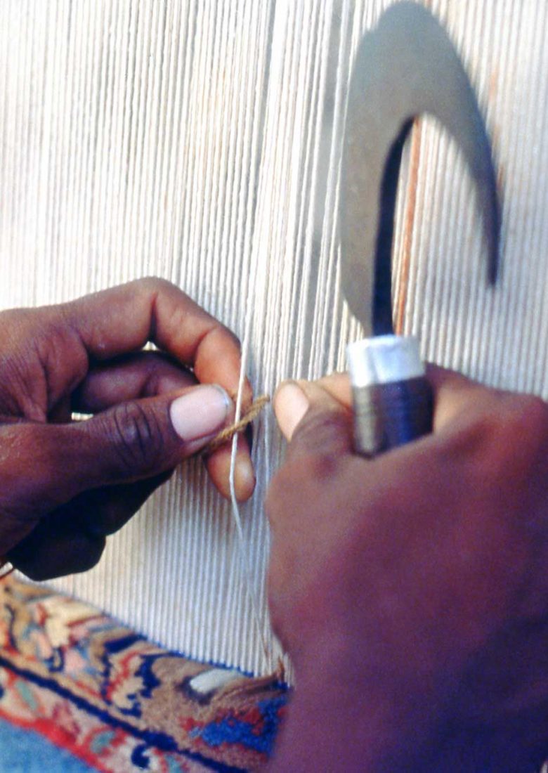 The weaver makes an asymmetrical Persian knot, then cuts the thread with his churi.