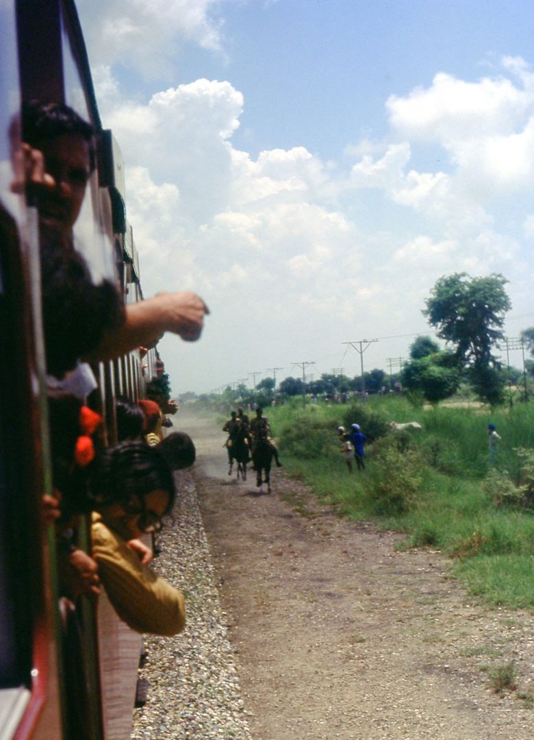 Soldiers on horseback gallop alongside the train, slowly overtaking